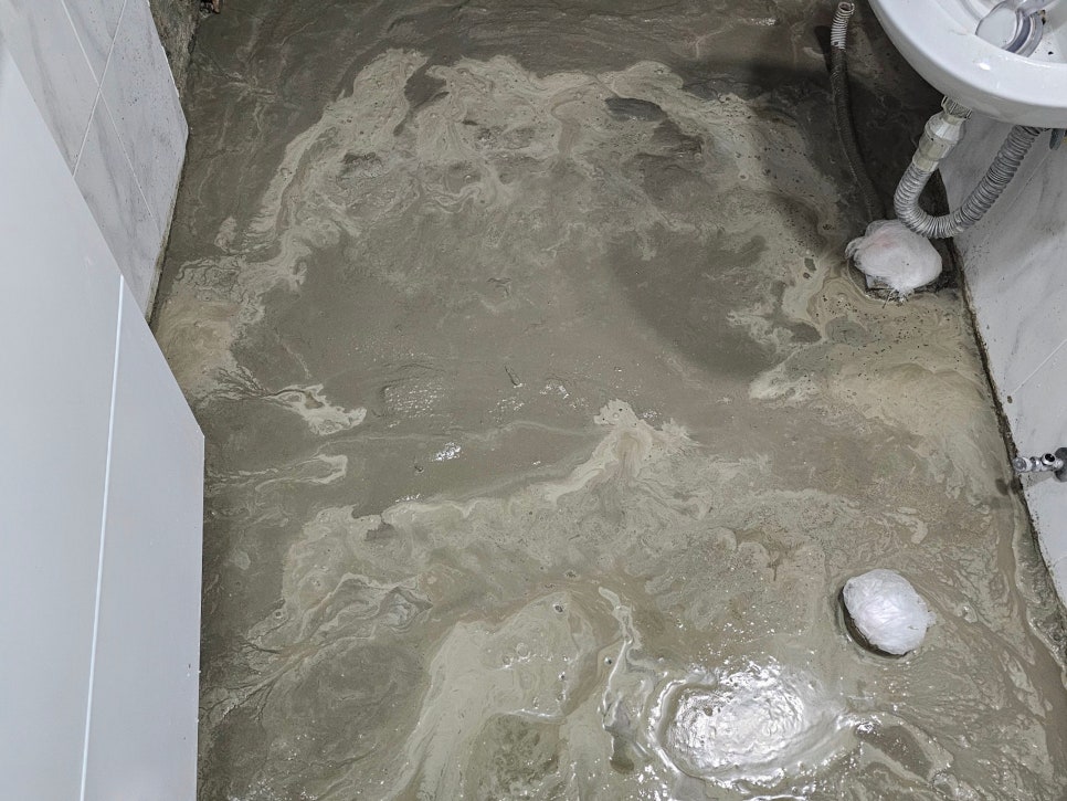 물이 흐르는 바닥과 수도꼭지, 세면대가 있는 욕실