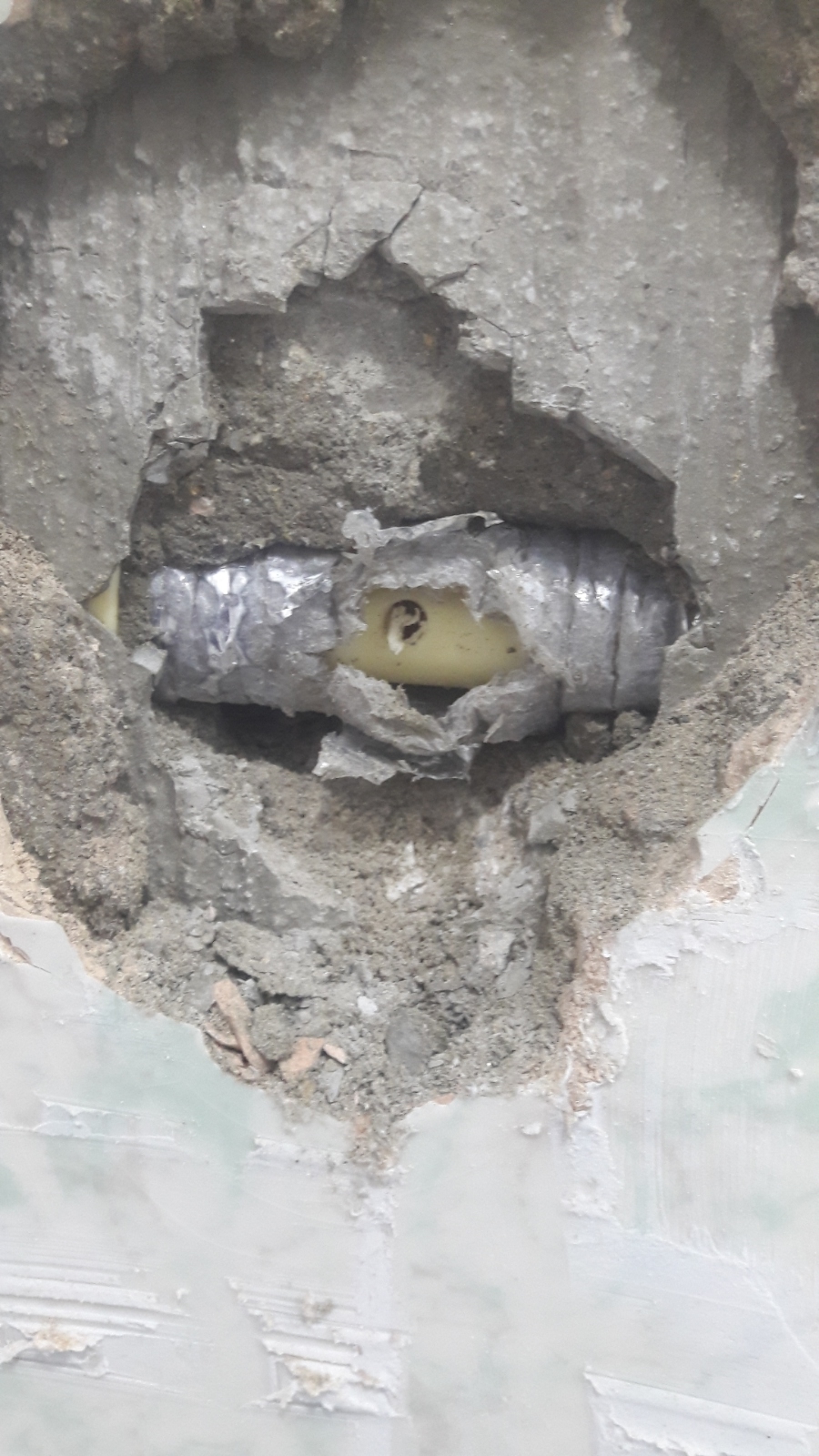 크랙된 벽면에 노출된 파이프와 고정된 금속관