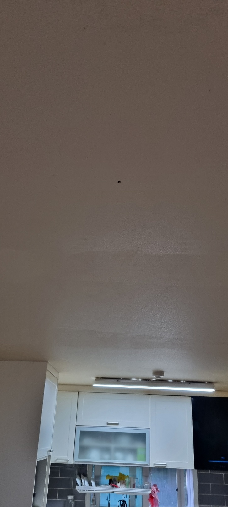 작은 검은 점과 넓은 색 차이가 보이는 주방 천장과 일자 조명