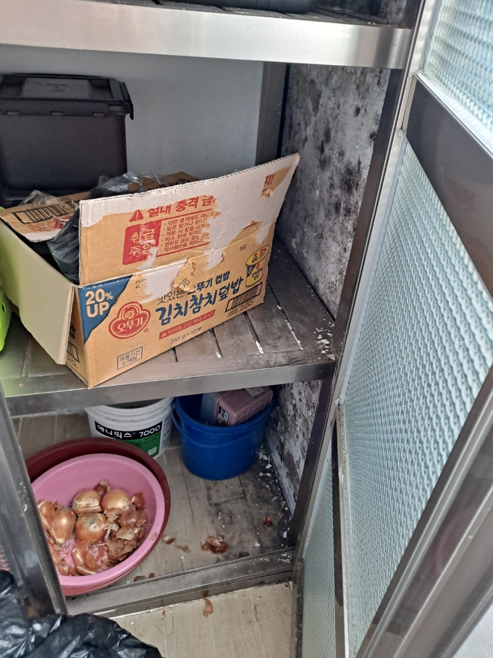 상자와 용기가 놓인 선반 옆 벽의 검은 얼룩과 벗겨진 표면