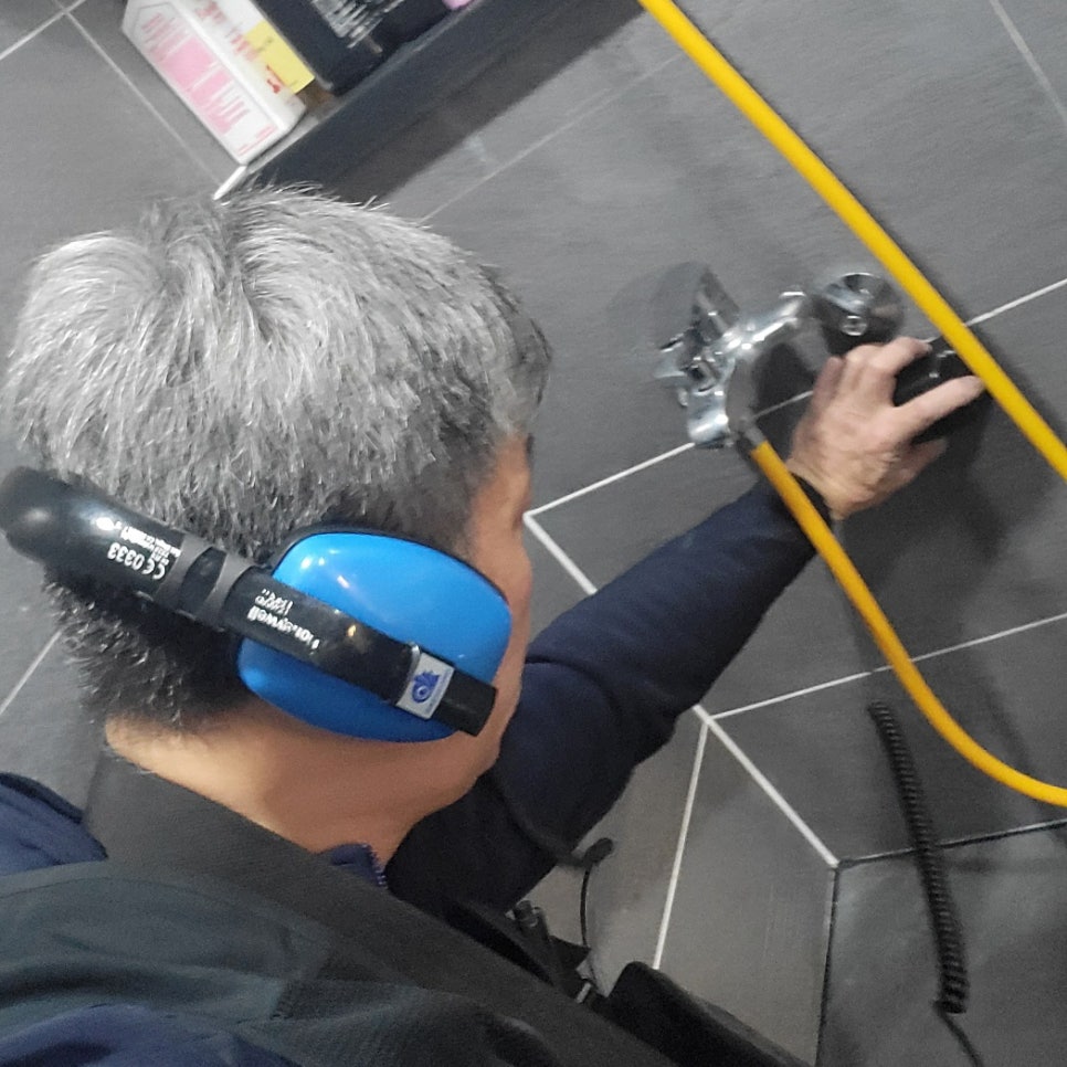 수전 오른쪽 연결부 가까이에 검은 장치를 대고 점검하는 모습