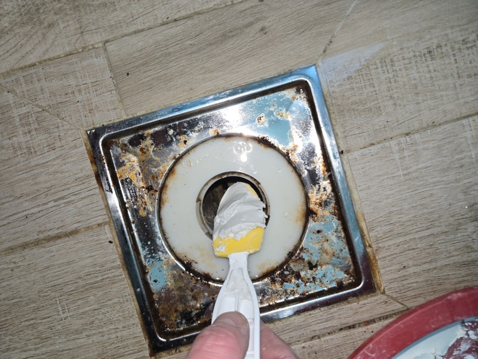 회백색 재료가 묻은 주걱을 배수구 입구에 대고 있는 모습