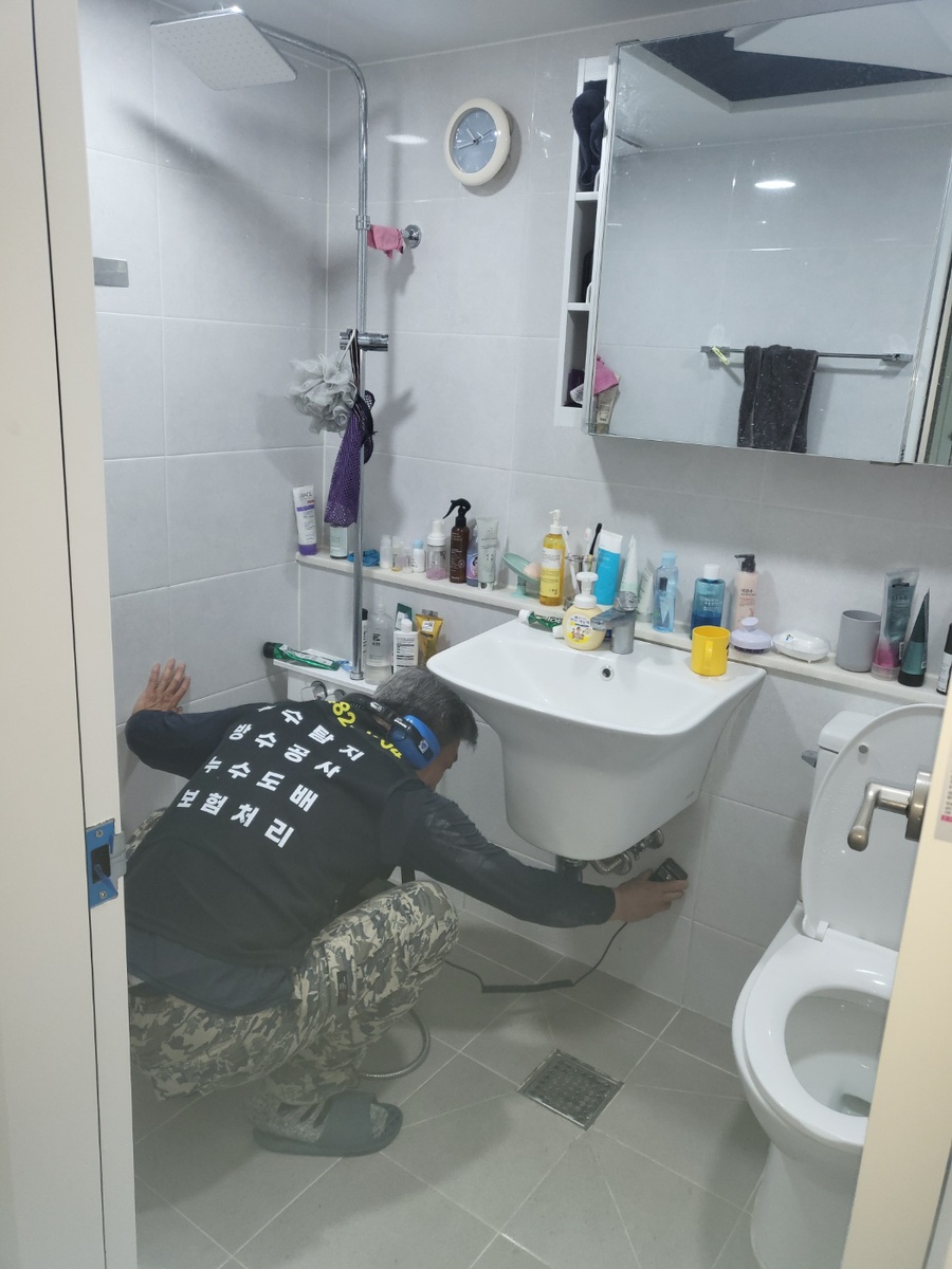 세면대 아래 벽에 탐지부를 대고 확인하는 모습