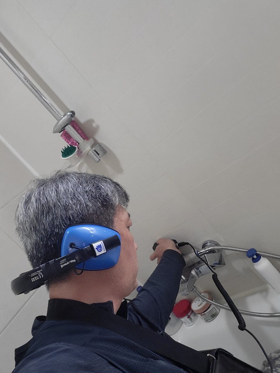 샤워 수전 주변을 유선 장비로 살피는 작업자