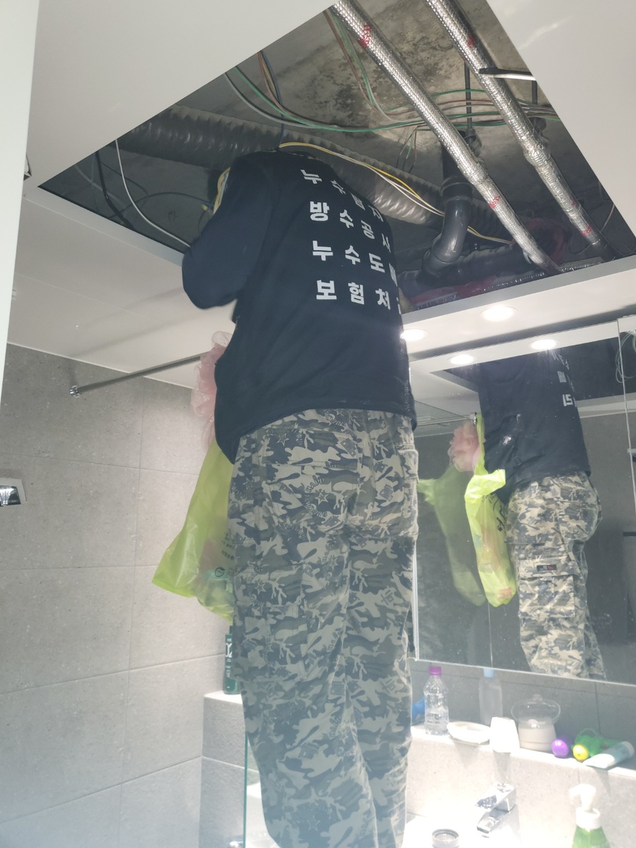 열린 욕실 천장 내부에서 작업하는 모습