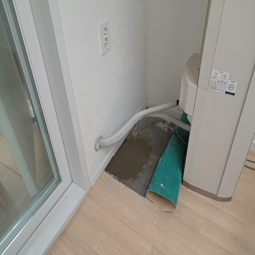 에어컨 옆 장판이 걷힌 바닥과 가운데의 짙은색 평평한 면