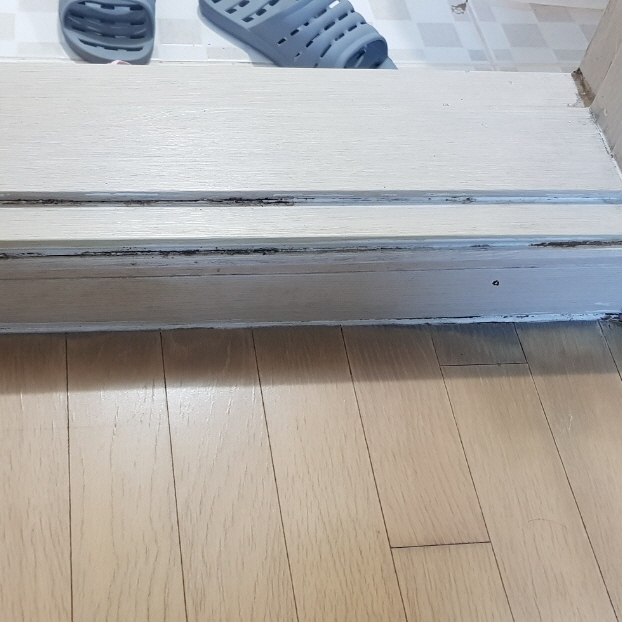 검은 자국과 표면 마감 손상이 보이는 욕실 문턱과 바닥 경계