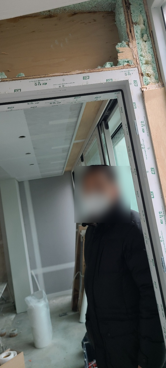 상부와 측면 마감이 열린 창호 주변의 목재와 연녹색 충전재