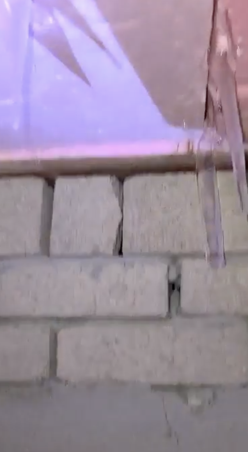 블록 벽 상단 오른쪽에 길게 매달린 투명한 물체