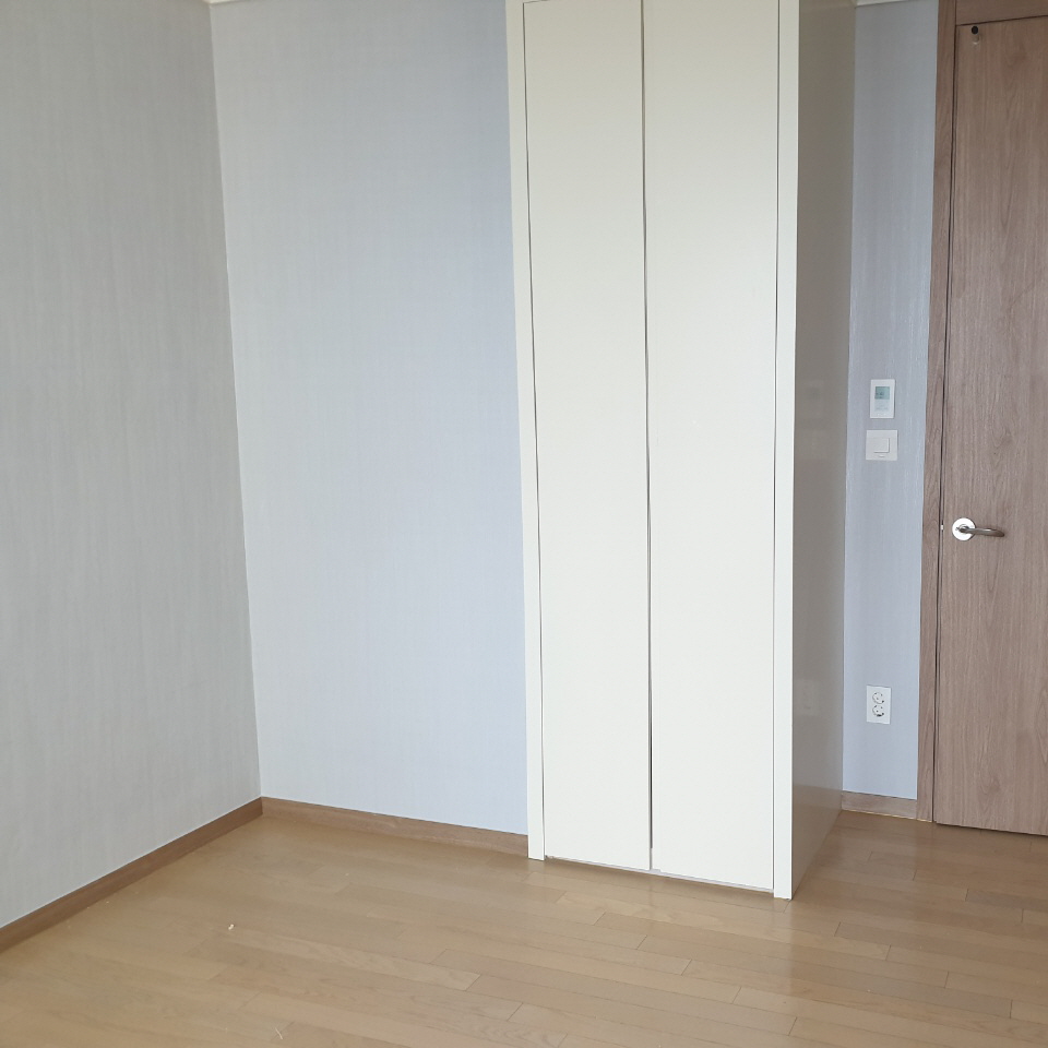회색 벽 모서리와 흰색 수납장, 목재 문 앞의 나무색 바닥